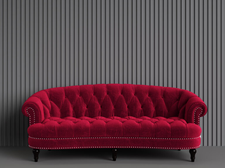 Luxurious red velvet Chesterfield sofa with deep tufting, a stunning focal point against a ribbed gray wall.
