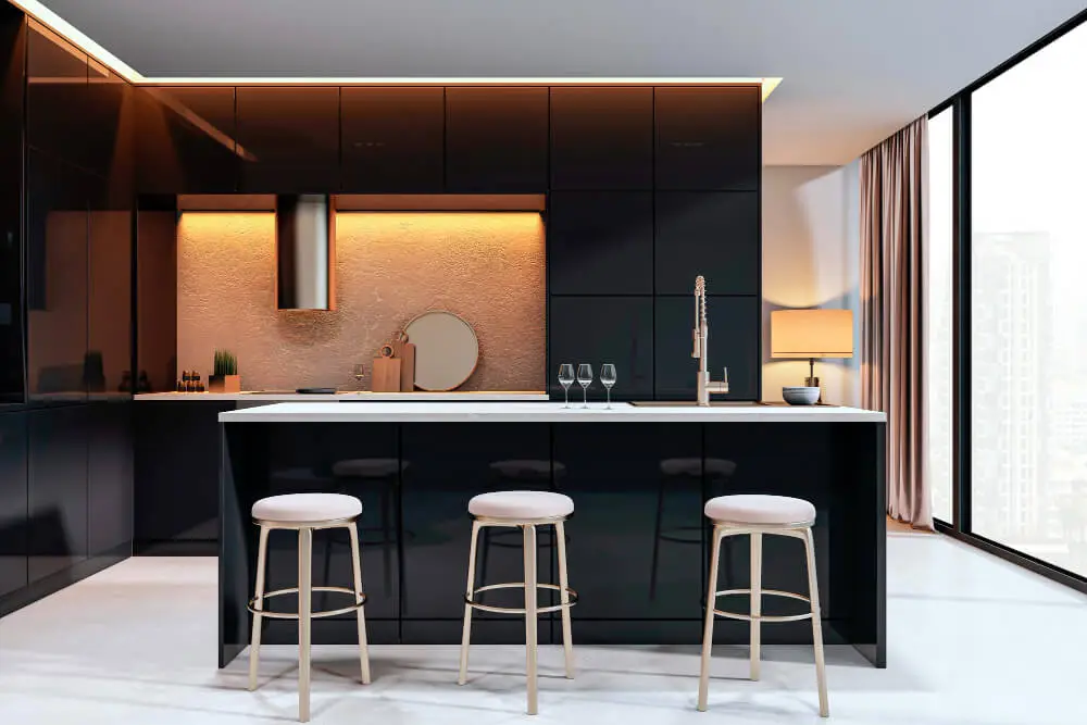 Modern black kitchen with white island, warm lighting, and three upholstered bar stools by a large window.