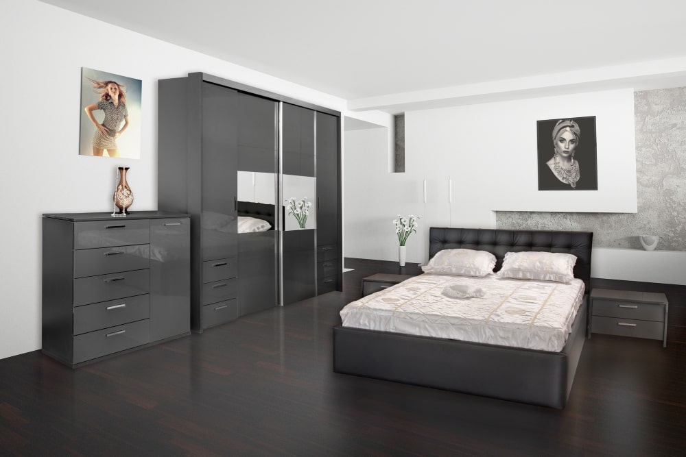 A cozy bedroom featuring a neatly made bed, a wooden dresser, and a wall-mounted mirror reflecting the room's decor.