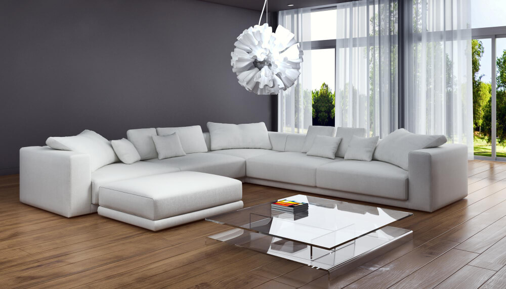 A chic modern living room with a spacious white sectional sofa, a glass coffee table, and a unique pendant light